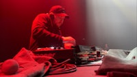 a man in a hat playing a dj set in front of a red light